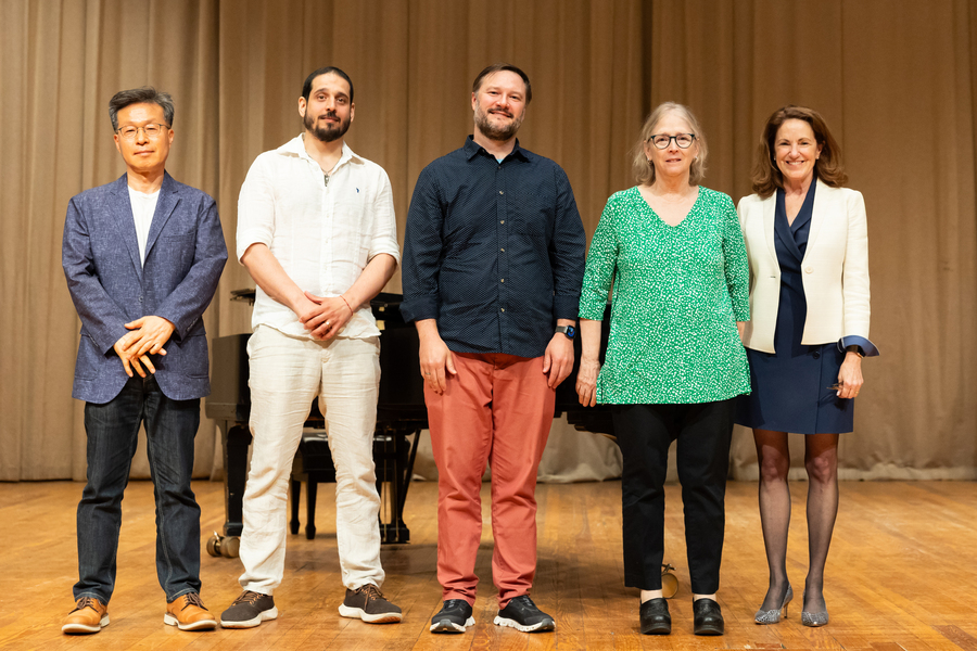 A group of five people standing on a stage together.